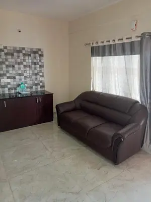 a brown couch in a living room with a window at Pinehill Suites in Ooty
