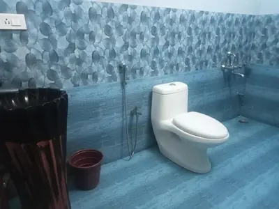 a bathroom with a toilet and a blue wall at Pinehill Suites in Ooty