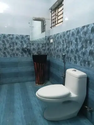 a bathroom with a white toilet and a mirror at Pinehill Suites in Ooty
