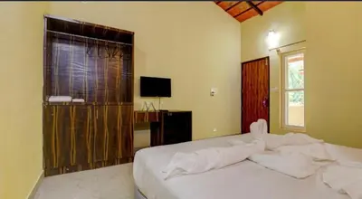 a bedroom with a white bed and a television at Lazo Areca Resort , Coorg in Madikeri