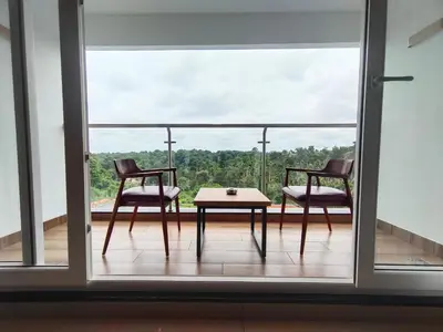 two chairs and a table on a balcony with a view at Hotel Saffron Wayanad in Sultan Bathery