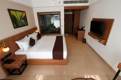 a bedroom with a bed and a flat screen tv at Hotel Saffron Wayanad in Sultan Bathery