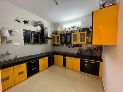 a kitchen with yellow cabinets and black counters at REHMANS HOMESTAY in Ooty
