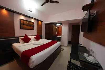 a bedroom with a large bed with red pillows at Hotel Jothi Grand in Coimbatore
