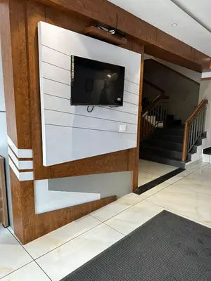 a flat screen tv on a wall with a staircase at Hotel Vrindavan in Wayanad