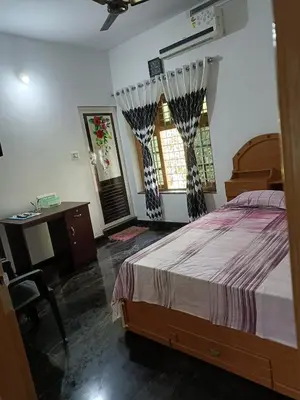 a bedroom with a bed and a desk and two windows at Oxygen Home Stay in Agali