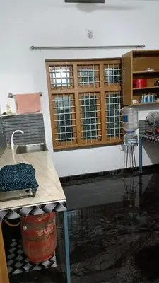 a kitchen with a counter and a table and some windows at Oxygen Home Stay in Agali