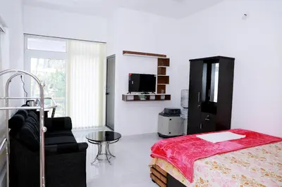 a bedroom with a bed and a chair and a tv at Oxygen Home Stay in Agali