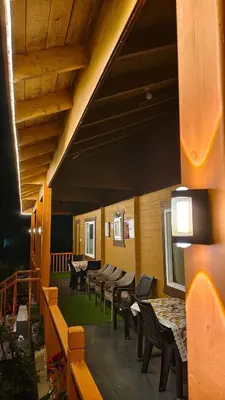 a room with tables and chairs and a balcony at The Laughing Woods AC Resort in Kotagiri