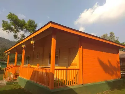 a small wooden house with a large porch at The Laughing Woods AC Resort in Kotagiri