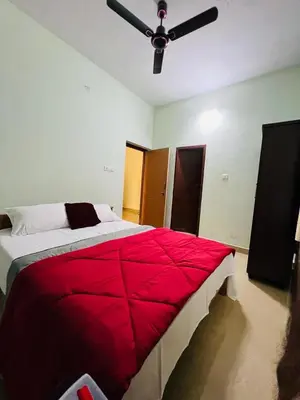 a bedroom with a red bed with a ceiling fan at Ocean Pearl in Kozhikode