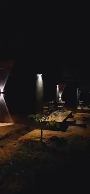 a group of tables in a dark room with lights at Bendheka - Cliff Front Cottages Coorg in Gonikoppal