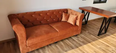 a brown leather couch sitting next to a wooden table at Bendheka - Cliff Front Cottages Coorg in Gonikoppal
