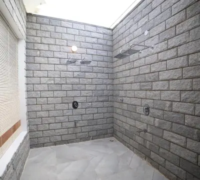 a bathroom with a shower with a brick wall at DWELLINGTON in Kotagiri