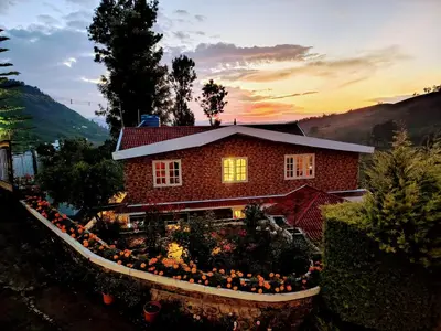 a house with a flower garden in front of it at INN THE MOUNTAIN'S in Kodaikānāl