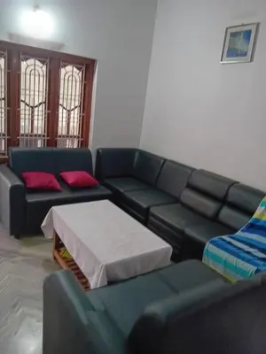 a living room with a green couch and red pillows at Moon moon Garden in Thamarassery