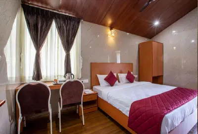 a bedroom with a bed and a desk with chairs at Blossom Inn in Coonoor